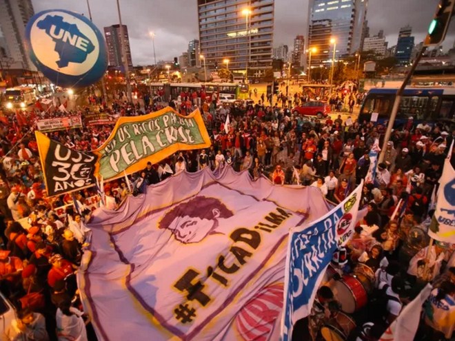 A anti-austerity protest in São Paulo on August 20, 2015. The large banner reads “Stay, Dilma” and the UNE balloon in the background stands for União Nacional Estudantil, or National Student Union. As opposed to the impeachment march, most protestors are dressed in red.
