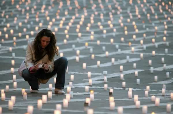A woman lights a candle in Bogotá to remember those killed in the conflict, amongst multiple other candles.