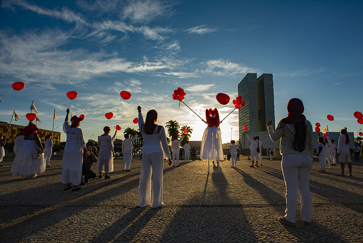 Dressed in white, with masks and red balloons, artists pay homage to the people killed by Covid-19 in Brazil, May 2020. 