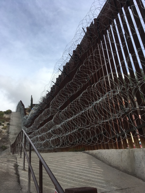 Photograph of the border wall with razor wire. 