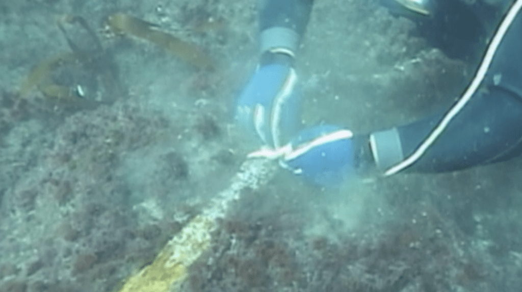 A diver ties a rope to retrieve a heavily rusted rail under Quintero Bay.