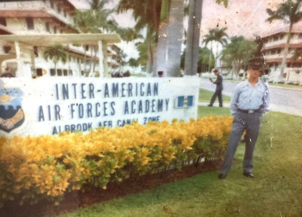 Molina posing in front of the sign for the Inter-American Air Forces Academy, Panama, 1974.