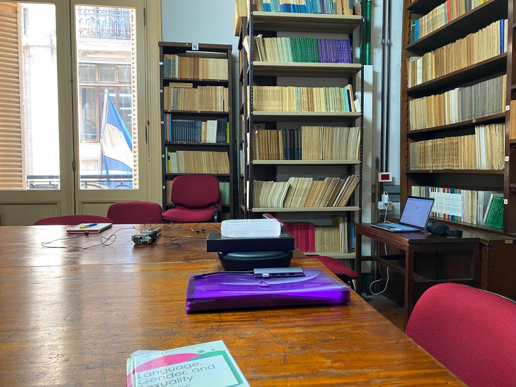 A large wooden table surrounded by bookcases with a small sidetable set up as a linguistic testing station with a laptop: the work environment inside the  Instituto de Lingüística in Buenos Aires. (Photo by Amber Galvano.)