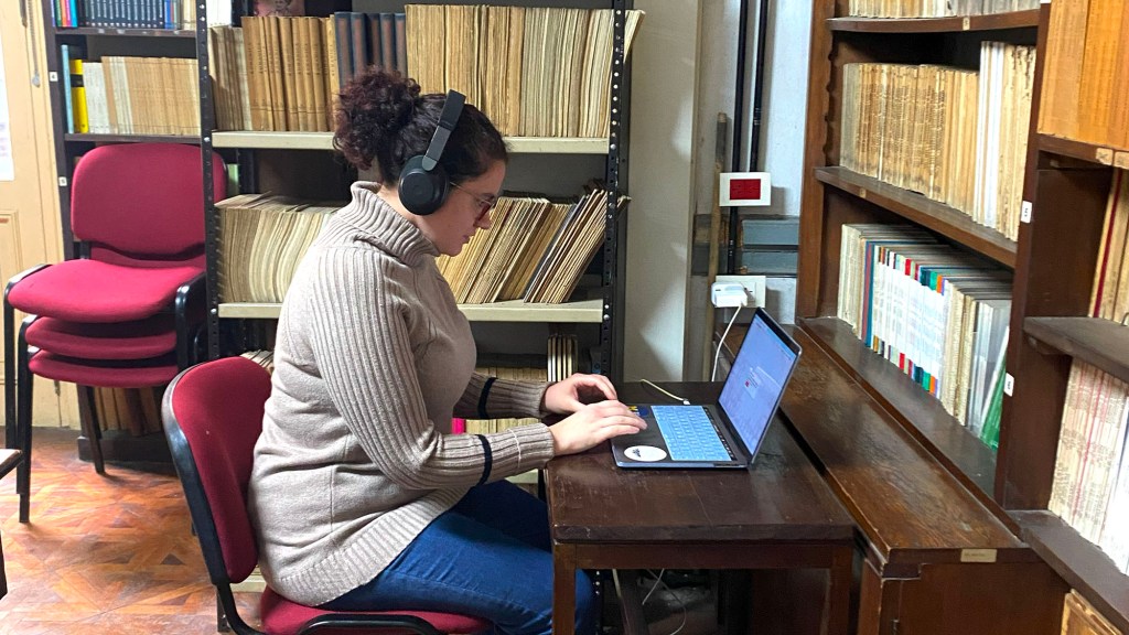A woman with headphones on working at a laptop computer: a participant listens to stimuli during the research on Porteño speech. (Photo by Amber Galvano.)