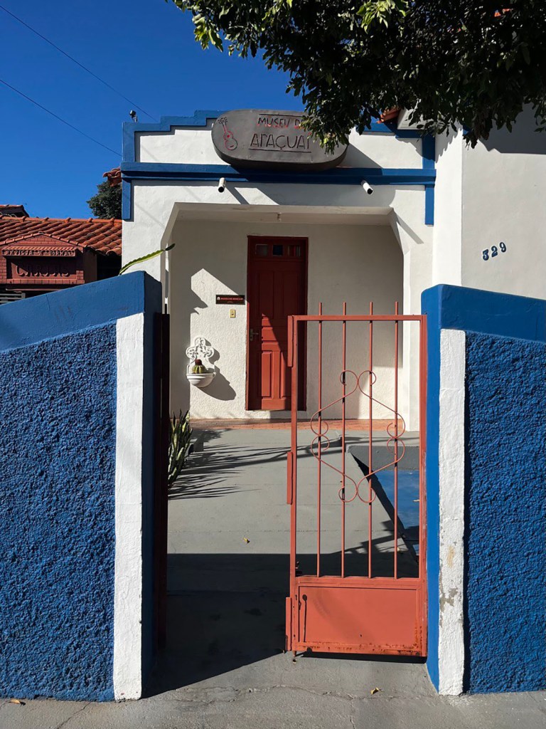 A blue wall and red gate mark the entrance to the Museu de Araçuaí.