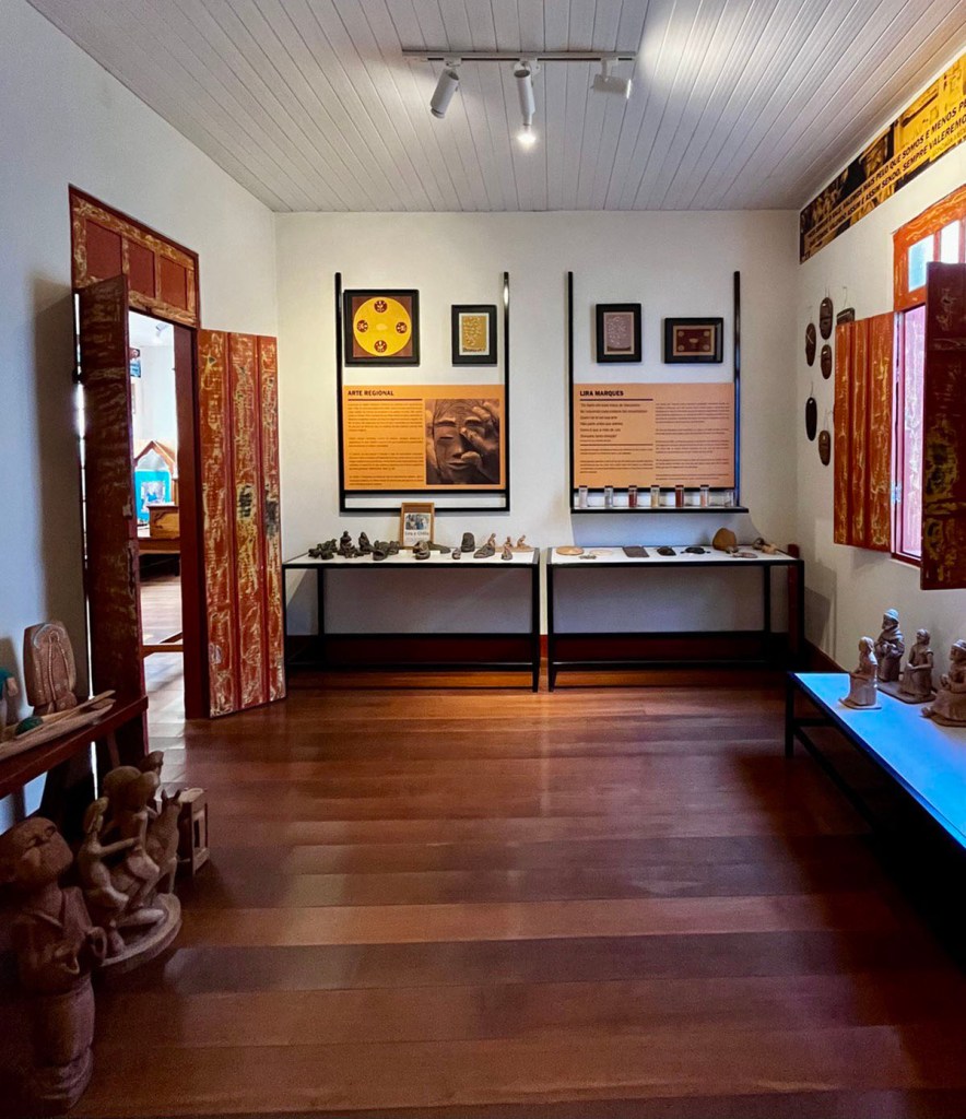 A room in the Museu de Araçuaí, with displays of artifacts and artwork, as well as large explanatory posters.
