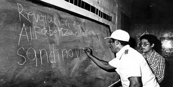 A man writing on a blackboard with chalk.