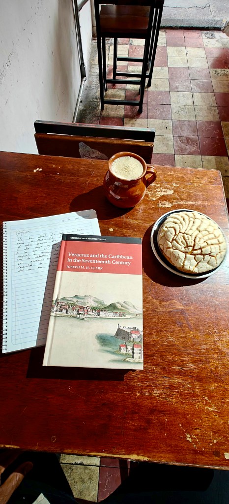 Pan dulce and a coffee with a book on Veracruz sitting on a table.