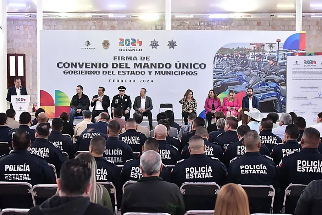 A formal event in Durango featuring a signing ceremony for a public safety agreement, with officials and police in attendance. The backdrop includes the event title and state insignias.