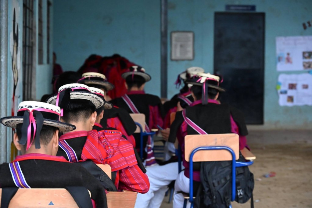Students in traditional Mam clothing sit in a classroom.
