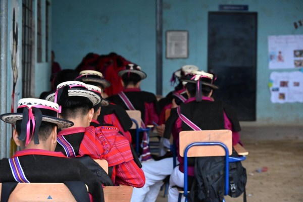 Maya Mam students in traditional clothing sit in a classroom.