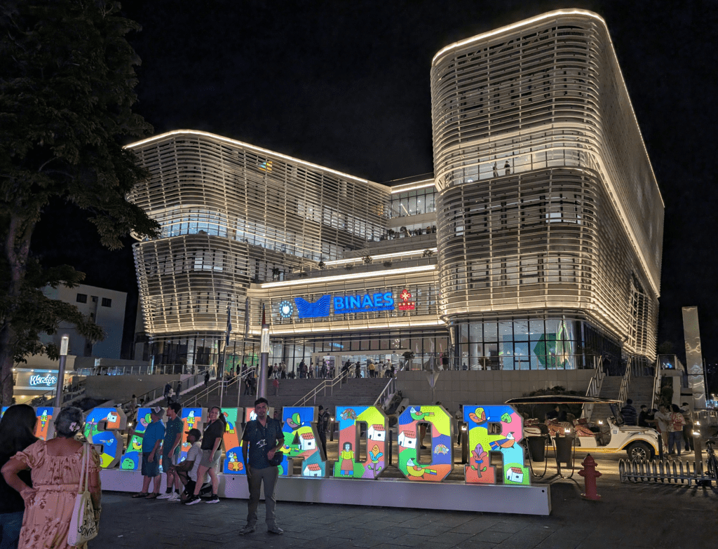 The outside of the very modern National Libary of El Salvador, with a colorful sign reading El Salvador in front.